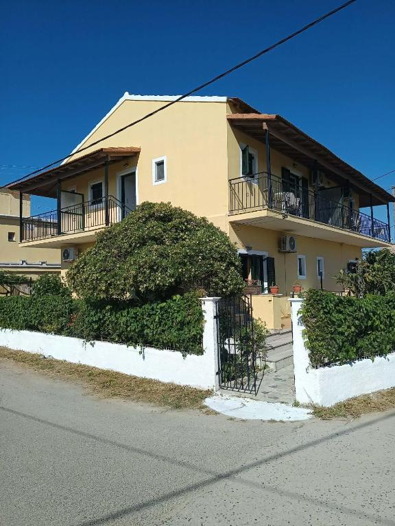 a large house with bushes in front of it at Dimosthenis Apartments in Agios Georgios