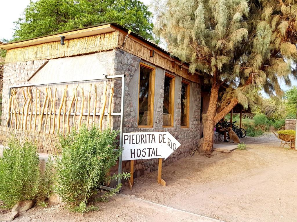 a building with a sign in front of a house at Hostal Piedrita de Rio in San Pedro de Atacama
