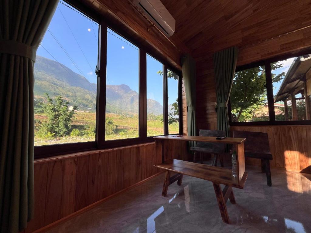 a room with a table and a bench and windows at Zay Riverside House in Tả Van