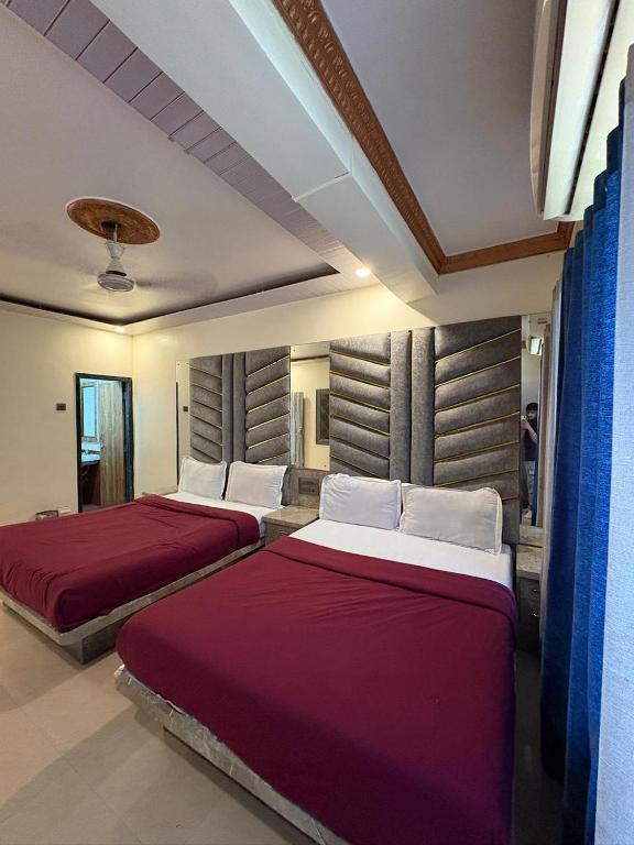 two beds in a room with red and white at Roshan Residency in Matheran