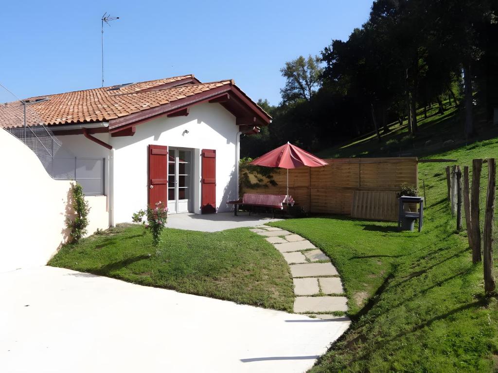 a small house with a red door in a yard at Gite Karrikartea in Saint-Pée-sur-Nivelle