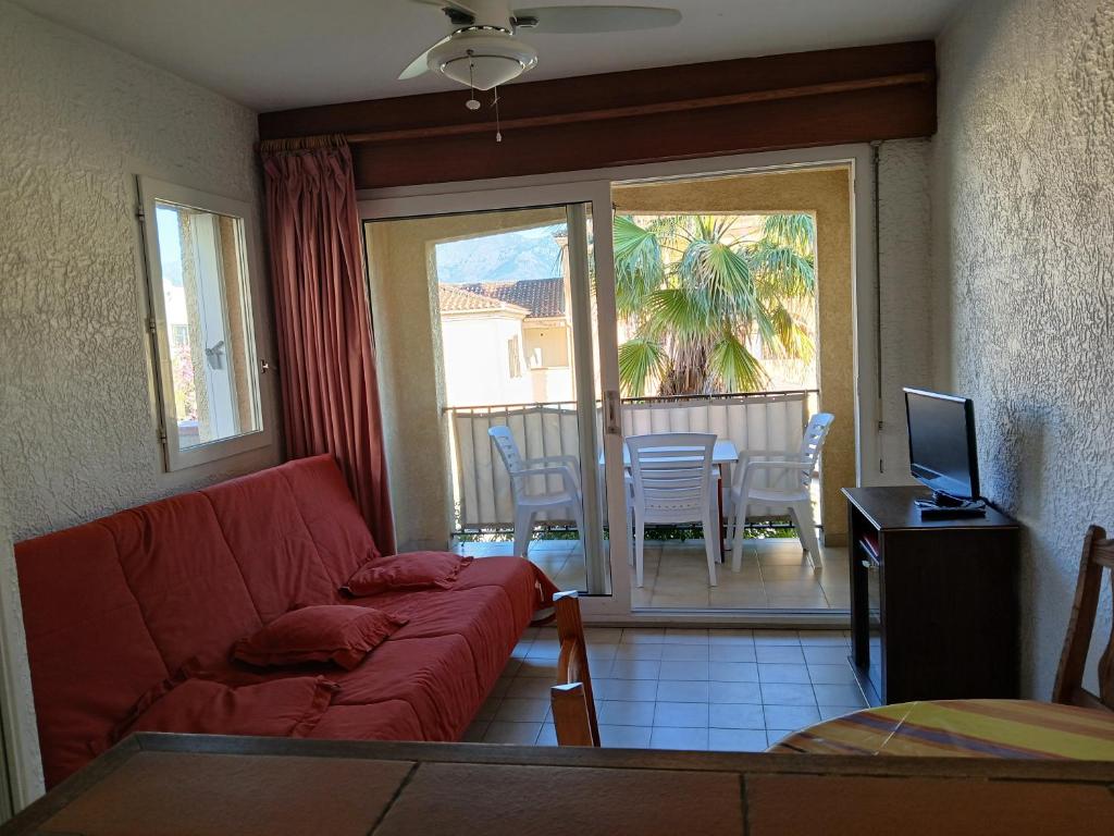 a living room with a red couch and a table with a television at Studio centre de calvi in Calvi