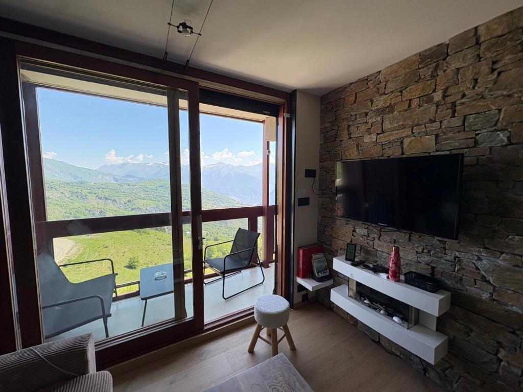 a living room with a tv and a large window at Flocons 48 in Villarembert