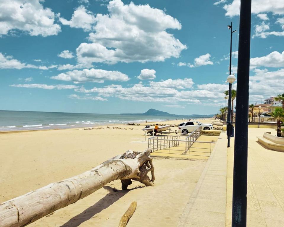 a log on the beach with a car parked at Miramar Playa confortable apartament in Miramar