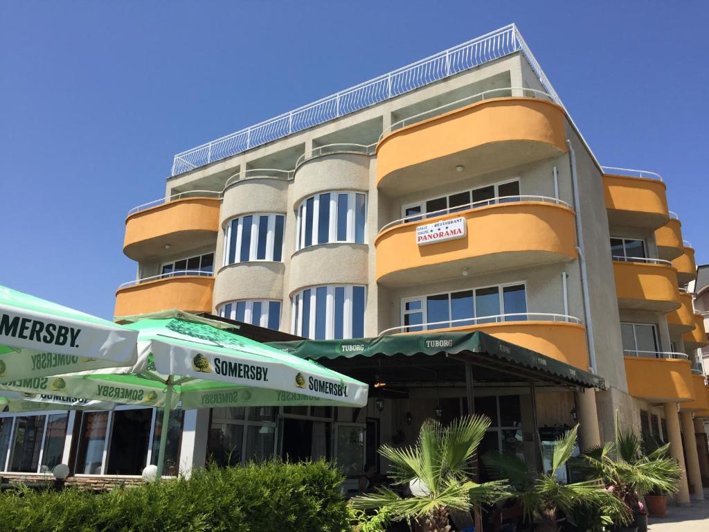 a yellow building with green umbrellas in front of it at Apartments Panorama Ravda in Ravda