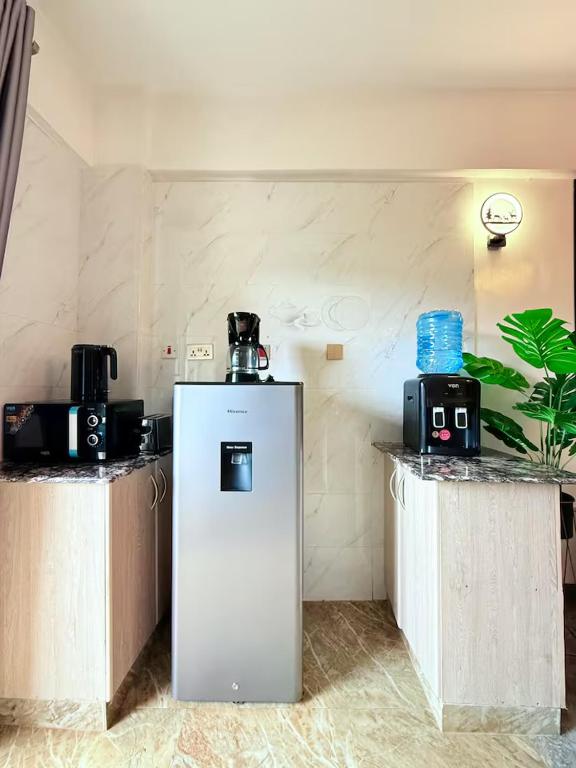 a refrigerator in a room with two tables and a plant at The best west residence in Ruaka