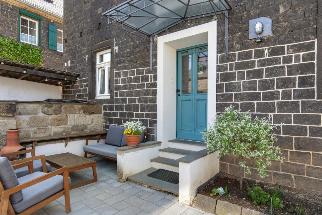 a patio with a blue door and two chairs at Eifel with Family in Thür
