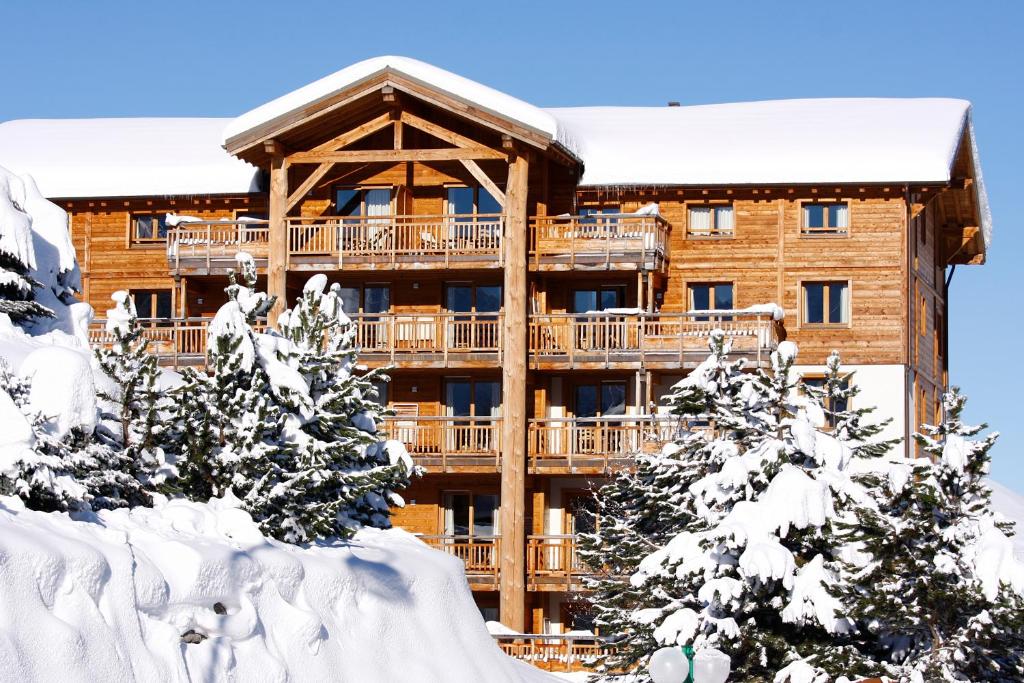 un lodge dans la neige avec des arbres enneigés dans l'établissement Vacancéole - Résidence l'Alba, à Les Deux Alpes