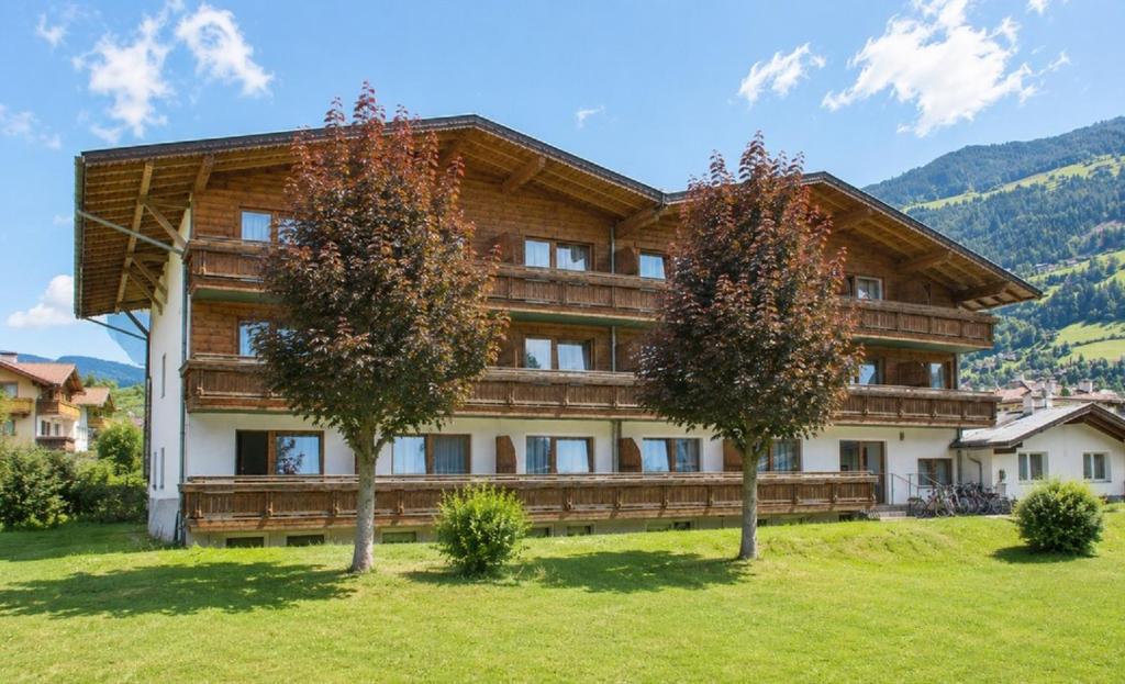 a large wooden building with trees in front of it at first mountain Hotel Zillertal in Aschau