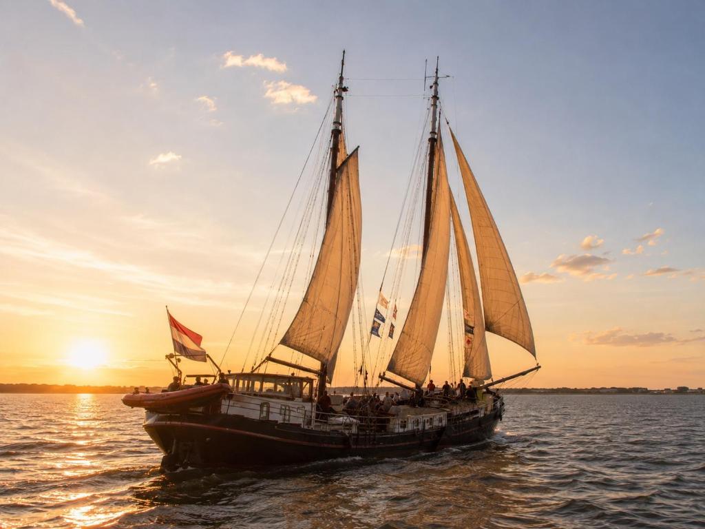 a sail boat in the water at sunset at Zeilschip de Alliantie Kampen in Kampen