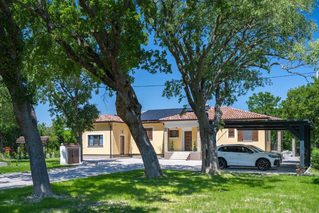 a house with a car parked in a yard at Villa Vivento in Vozilići