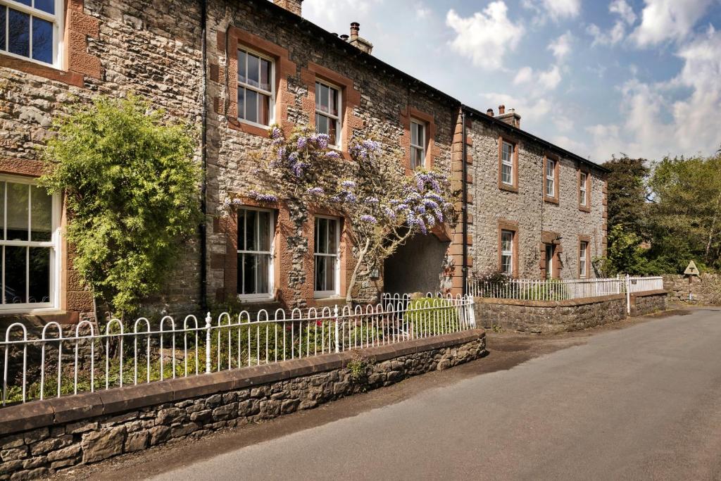 a brick building with a fence next to a street at Finest Retreats - Bourne Edge in Morland