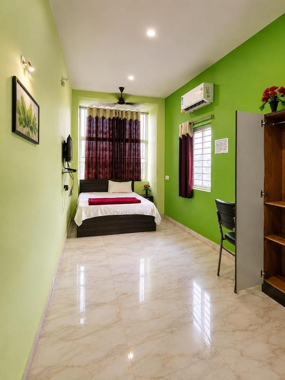 ein Schlafzimmer mit grünen Wänden, einem Bett und einem Stuhl in der Unterkunft Prasant Inn in Bhubaneshwar