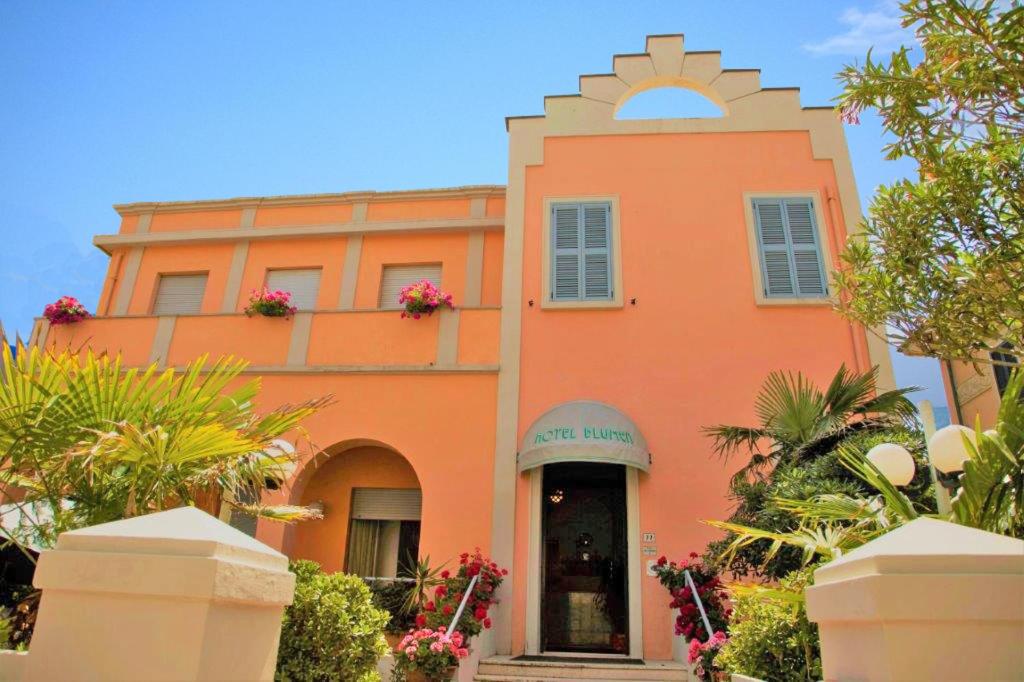un edificio arancione con piante di fronte di Amadei Hotel Blumen a Pesaro