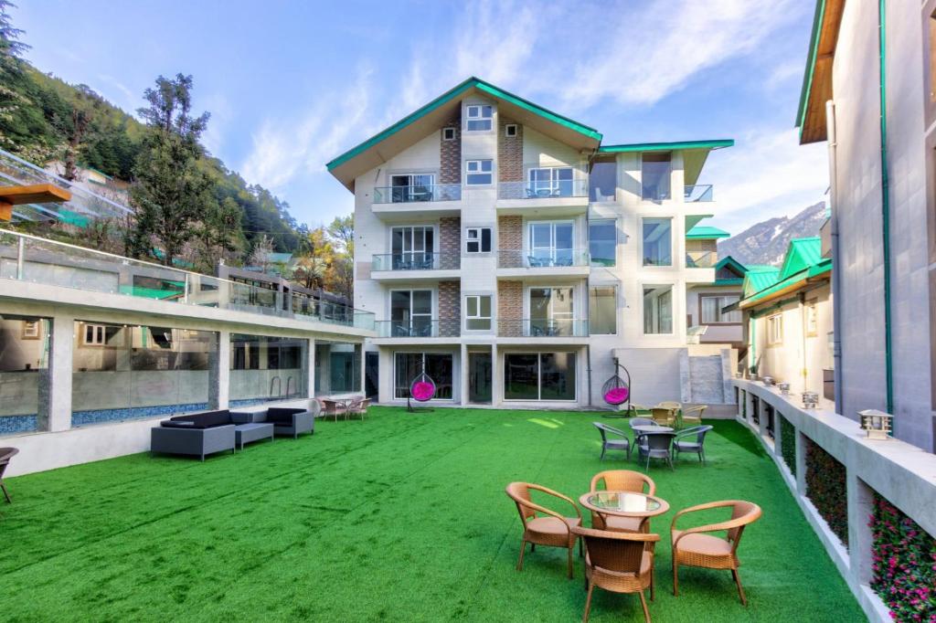 a large house with a green yard with chairs and tables at Kason Grand View Manali in Manāli