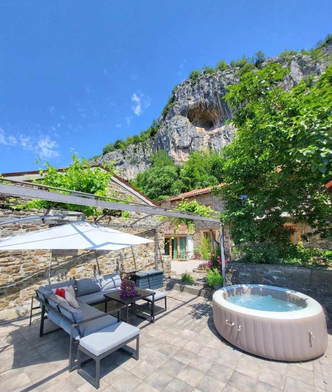 a patio with a hot tub and a table and chairs at Under the rock-jacuzzi-400y stone property in Osp