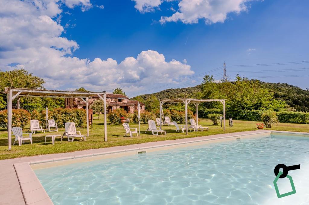 a swimming pool in a yard with chairs and a table at Hotiday Massa Marittima in Massa Marittima