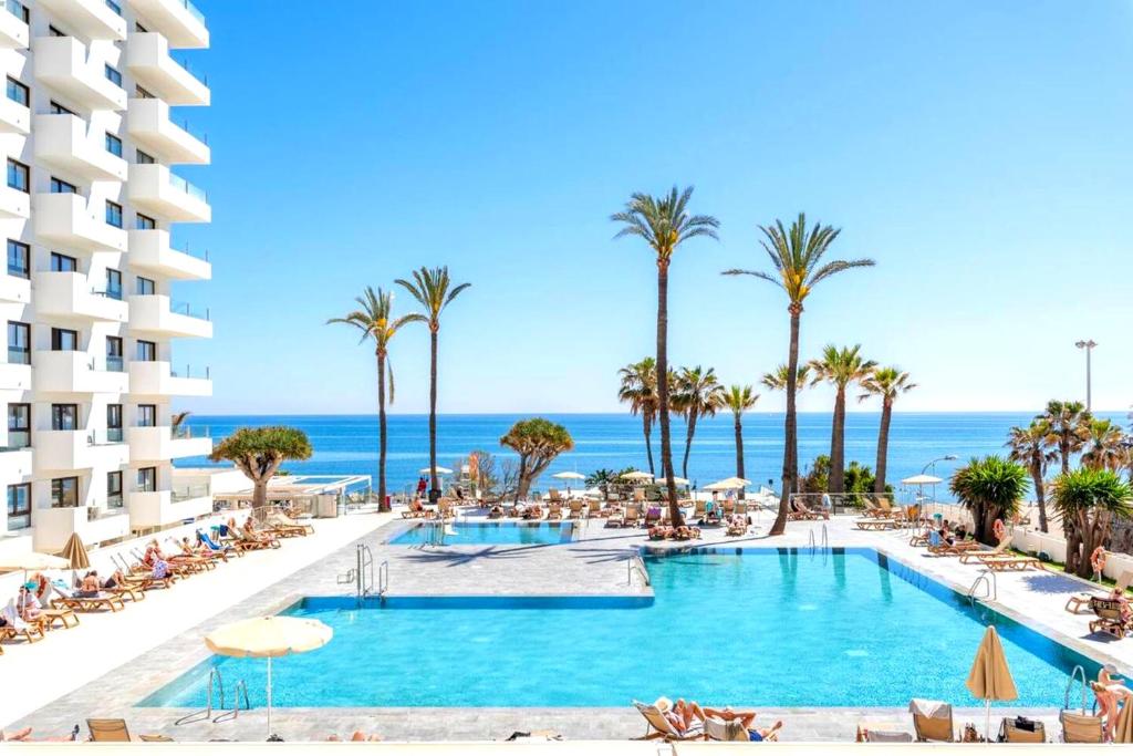 a view of the pool at the resort with palm trees and the ocean at Ocean House Costa del Sol apartamentos varios by Costa del Sol Stay in Torremolinos