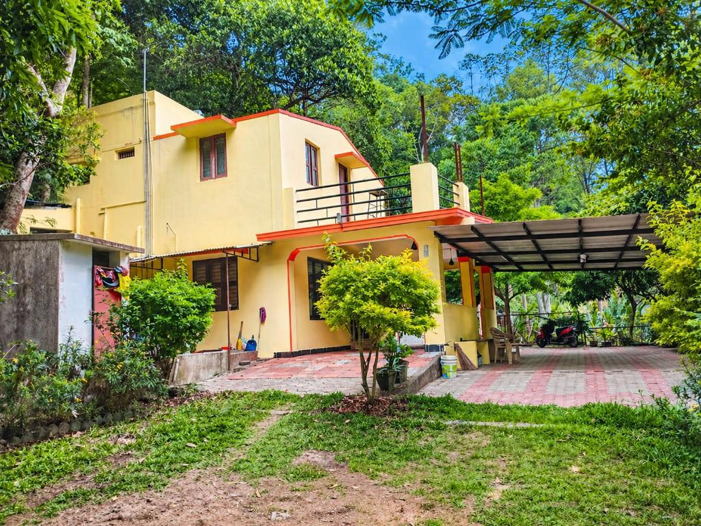 a yellow house with a porch and a driveway at Comfort Cottage in Yercaud