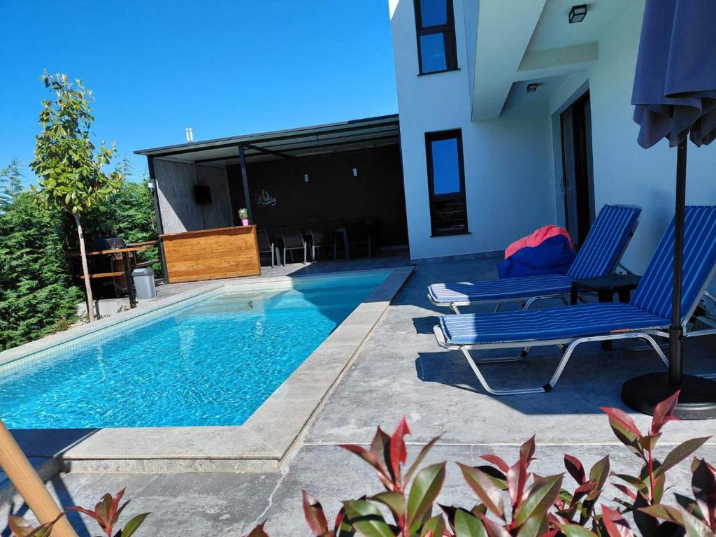 a swimming pool with two blue chairs next to a house at Villa Cadaques, private pool with heating and salt water in Lozenets
