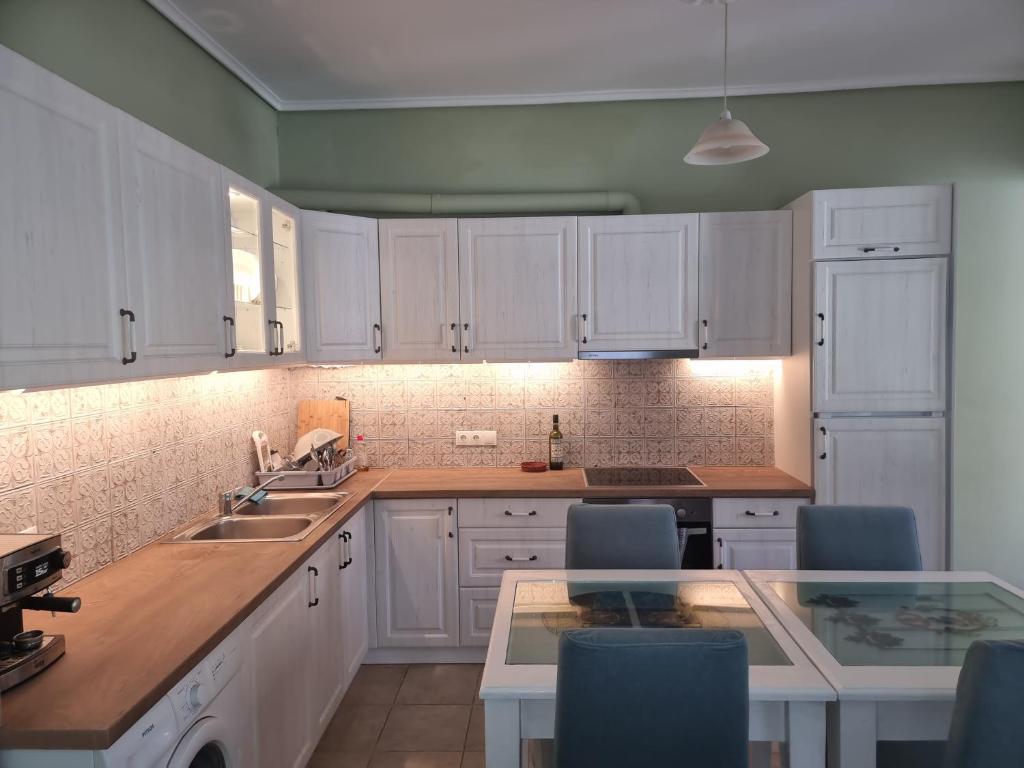 a kitchen with white cabinets and a sink and a table at Andros house in Andros
