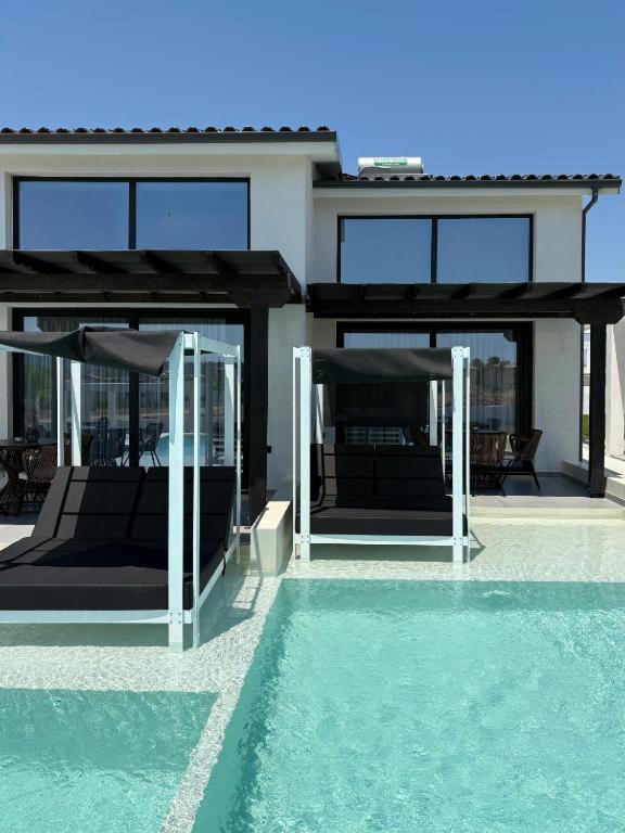 a house with glass doors and a swimming pool at Villa Eden in Kallithea Halkidikis