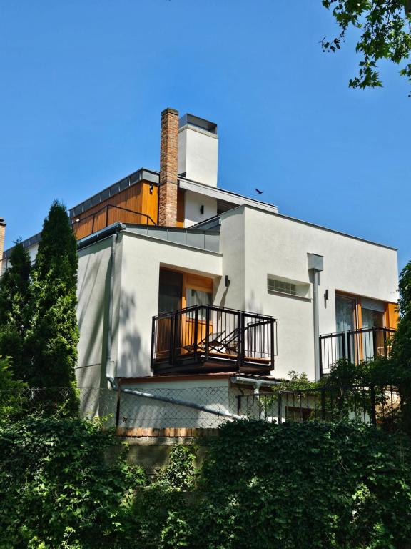 a white house with a chimney and a balcony at Platán Villa - Platán Tata in Tata