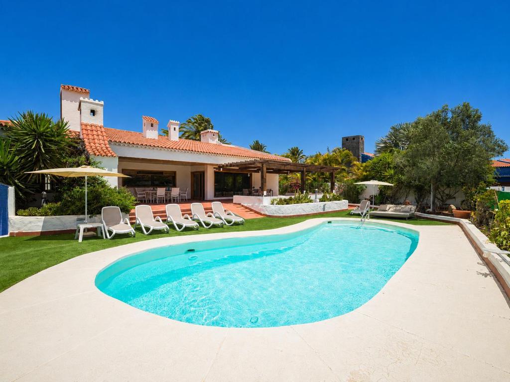 a swimming pool with chairs and a house at CASA GRAN CANARIA - Gran Canaria Stays in Maspalomas