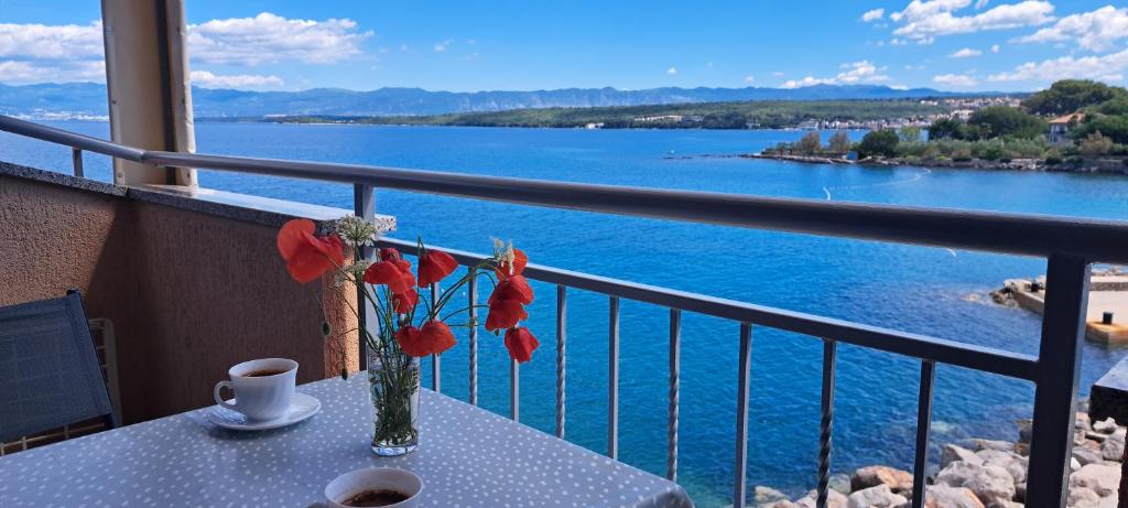 a table with a vase of flowers on a balcony at Apartment Mali Mol in Vantačići
