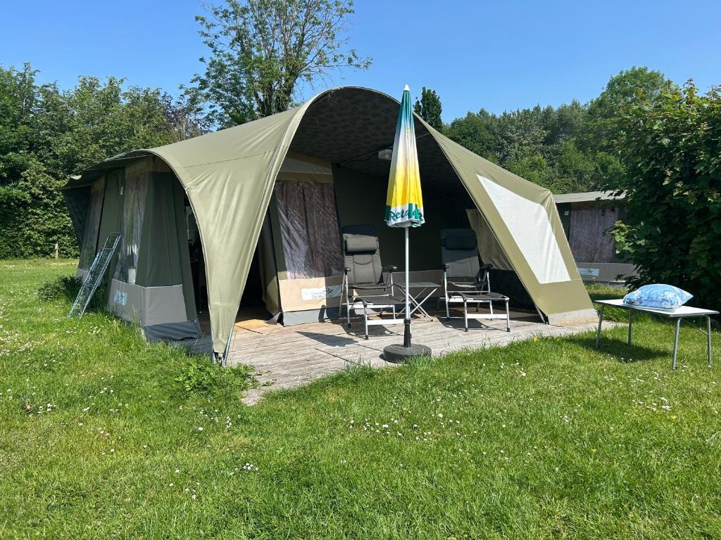a tent with chairs and an umbrella in a field at Camping De Meidoorn in Sluis
