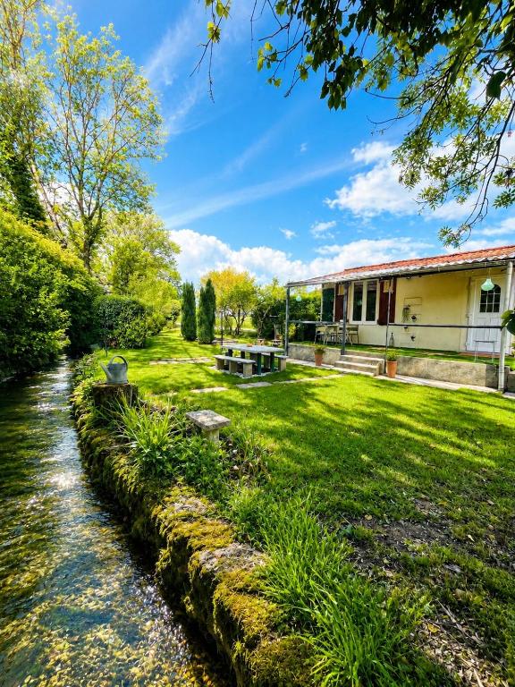 a garden with a stream in front of a building at La maisonnette au bord de l eau in Grimaucourt-près-Sampigny