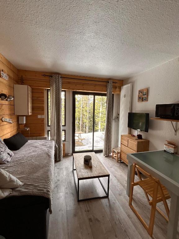 a living room with a couch and a table at Studio rez de jardin Praloup in Uvernet