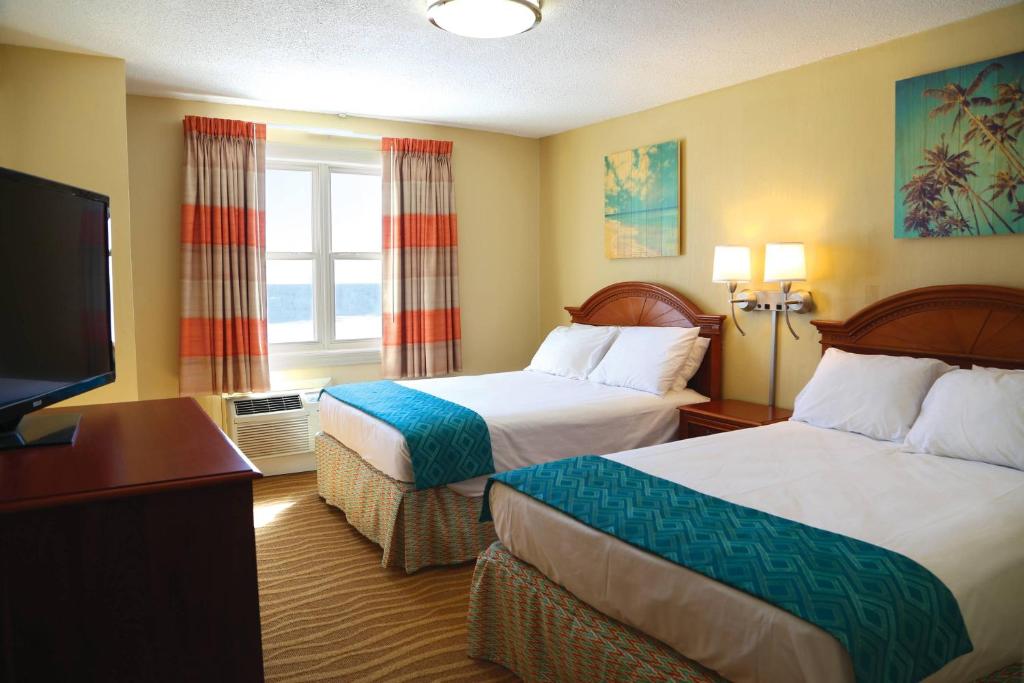 Habitación de hotel con 2 camas y TV de pantalla plana. en Plim Plaza Hotel en Ocean City