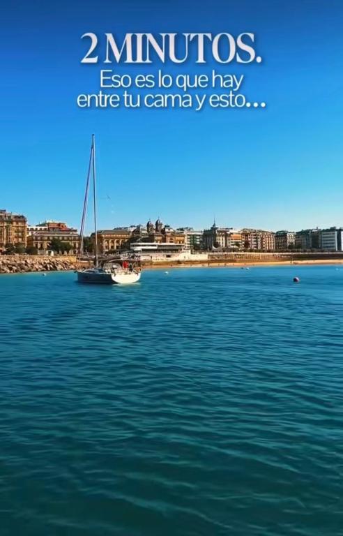 a boat in the water with a city in the background at Hotel Zaragoza Plaza in San Sebastián