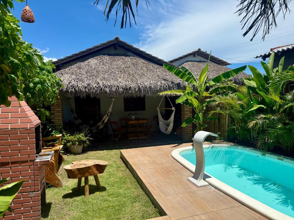 a villa with a swimming pool in front of a house at Chalé Lampião BG in Barra Grande