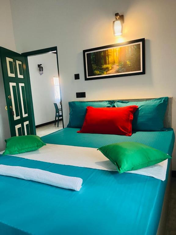 a blue bed with green and red pillows in a room at Knuckles Breeze Villas Kandy in Kandy