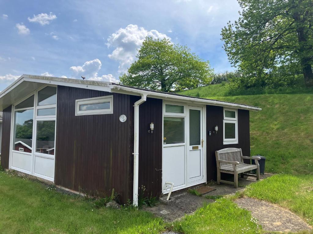 a brown and white shed with a bench in a yard at Elmrise View in Llanstephan
