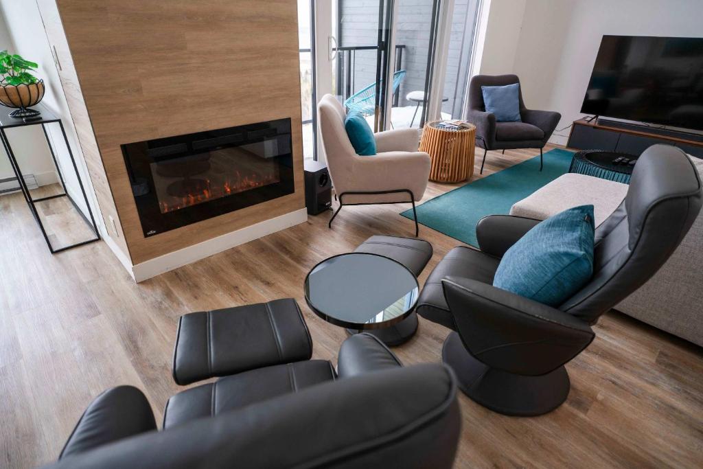 a living room with a couch and chairs and a fireplace at 407 - Luxury Condo - Incredible View & Pool in Baie-Saint-Paul