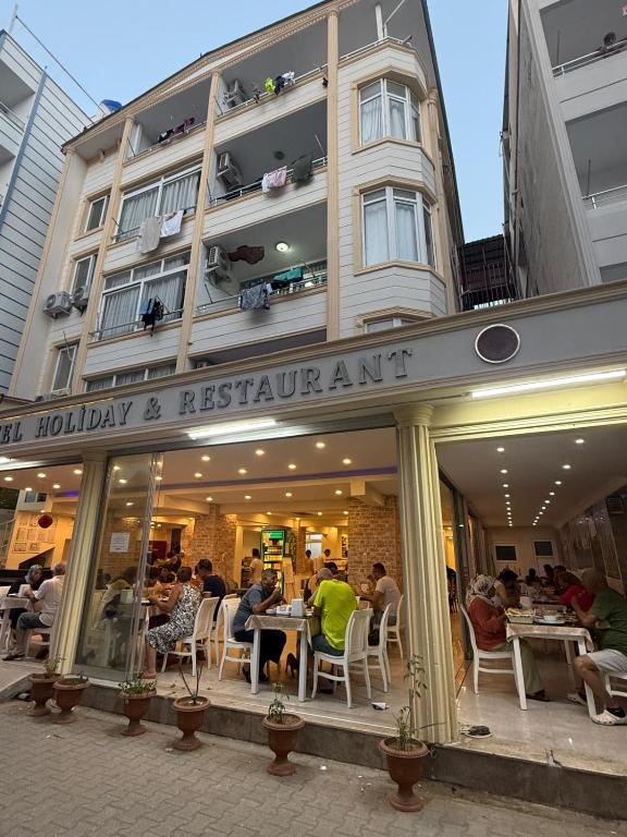 a restaurant with people sitting at tables in front of a building at Holiday Hotel in Erdemli