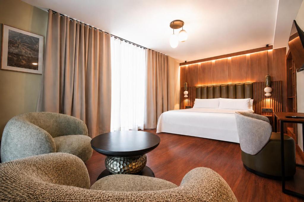 a hotel room with a bed and chairs and a table at Hotel El Nogal in Peligros