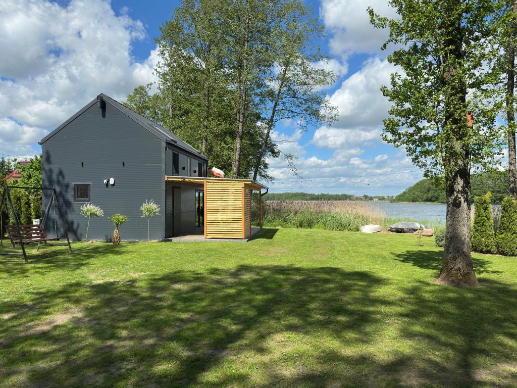 a gray house with a wooden garage next to a lake at Mazurski Chill House in Małkinie