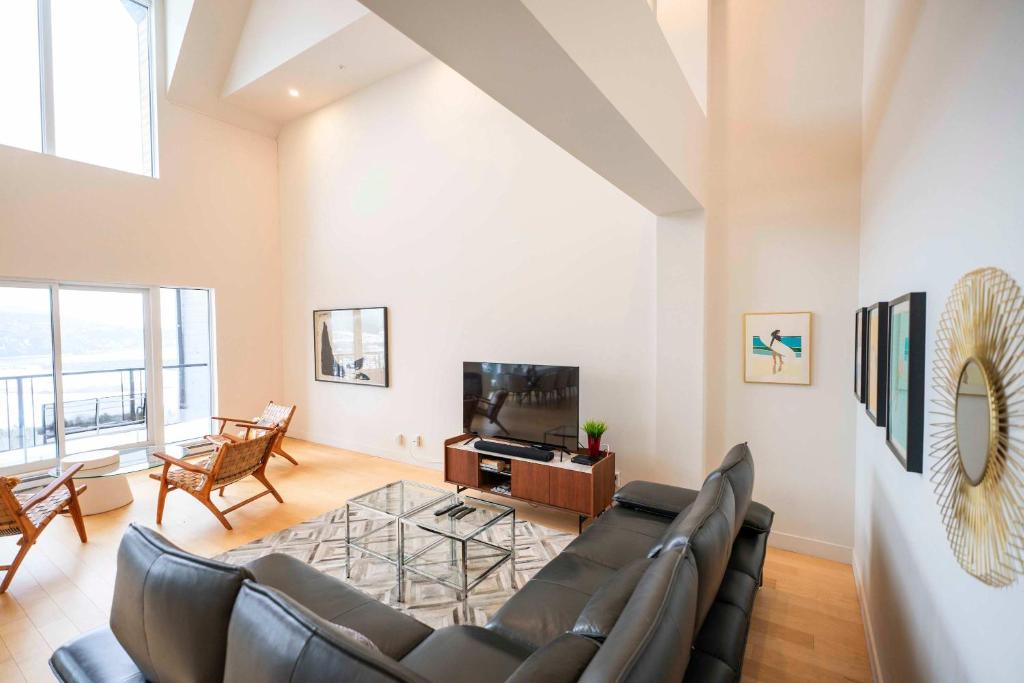 a living room with a couch and a tv at 405 - Modern and Luxury Condo - View and Pool in Baie-Saint-Paul
