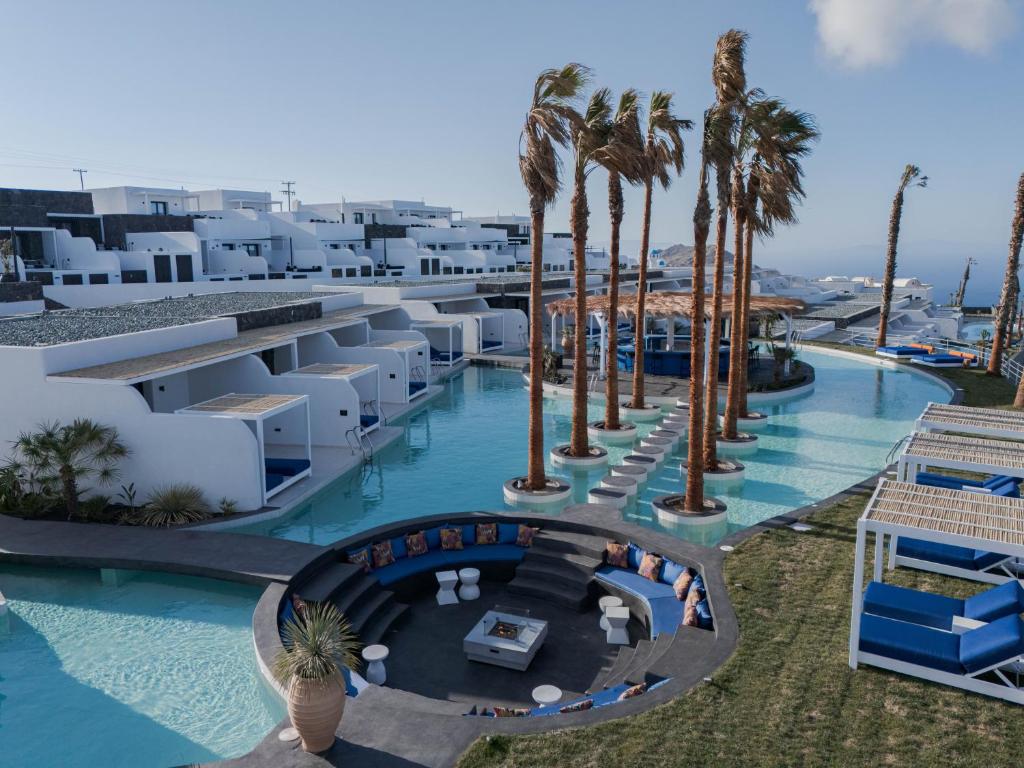an aerial view of a resort swimming pool with palm trees at Cresanto Luxury Suites in Imerovigli