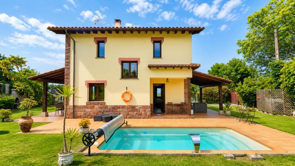 a villa with a pool in front of a house at Villa Los Bufones de Pria in Llames de Pría