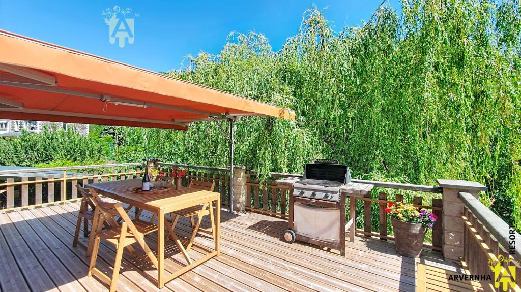 a wooden deck with a grill and a table and a barbecue at Gîte Scopa in Murol