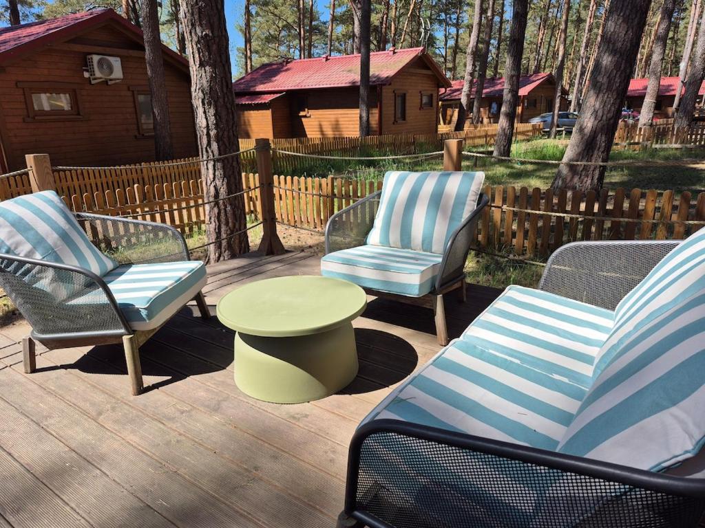 three chairs and a table on a deck with a house at Pine House Domek 22 in Borsk