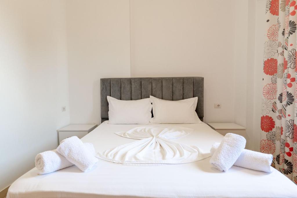 a white bed with two white towels on it at Center Apartments in Ksamil
