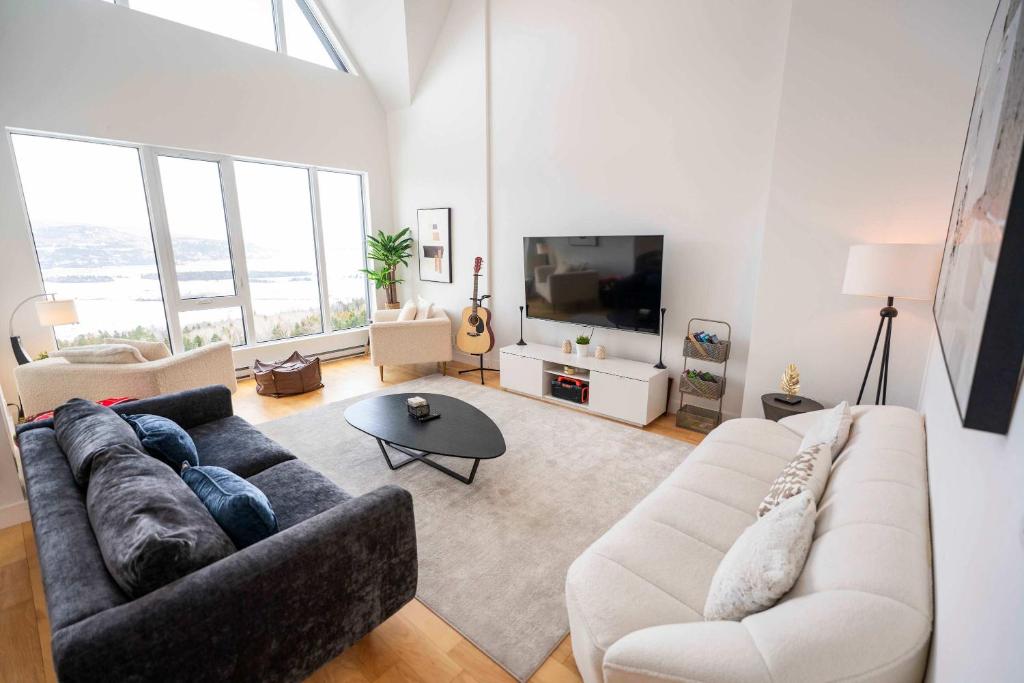 a living room with a couch and a tv at 403 - Luxury Condo - Incredible View & Pool in Baie-Saint-Paul
