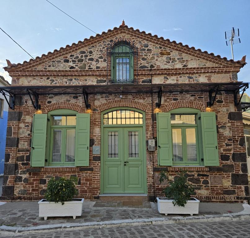 a brick building with green doors and windows at Petrino Guesthouse I Central Mytilini Stay in Pámfylla