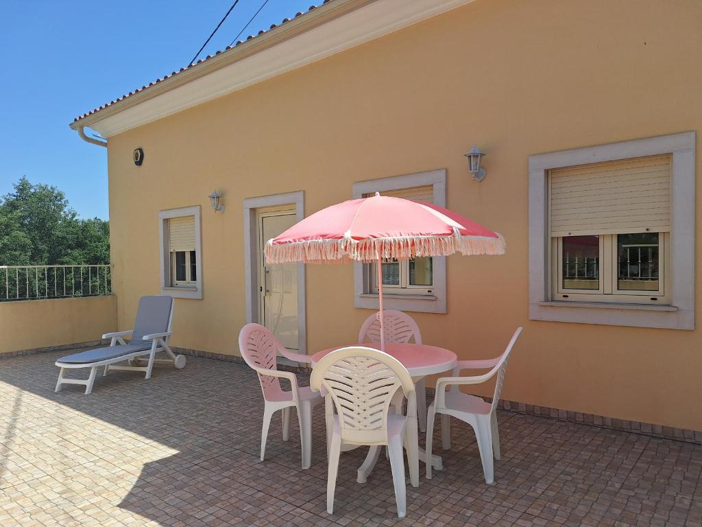 a table with chairs and an umbrella on a patio at Casa do Pastana in Ancião